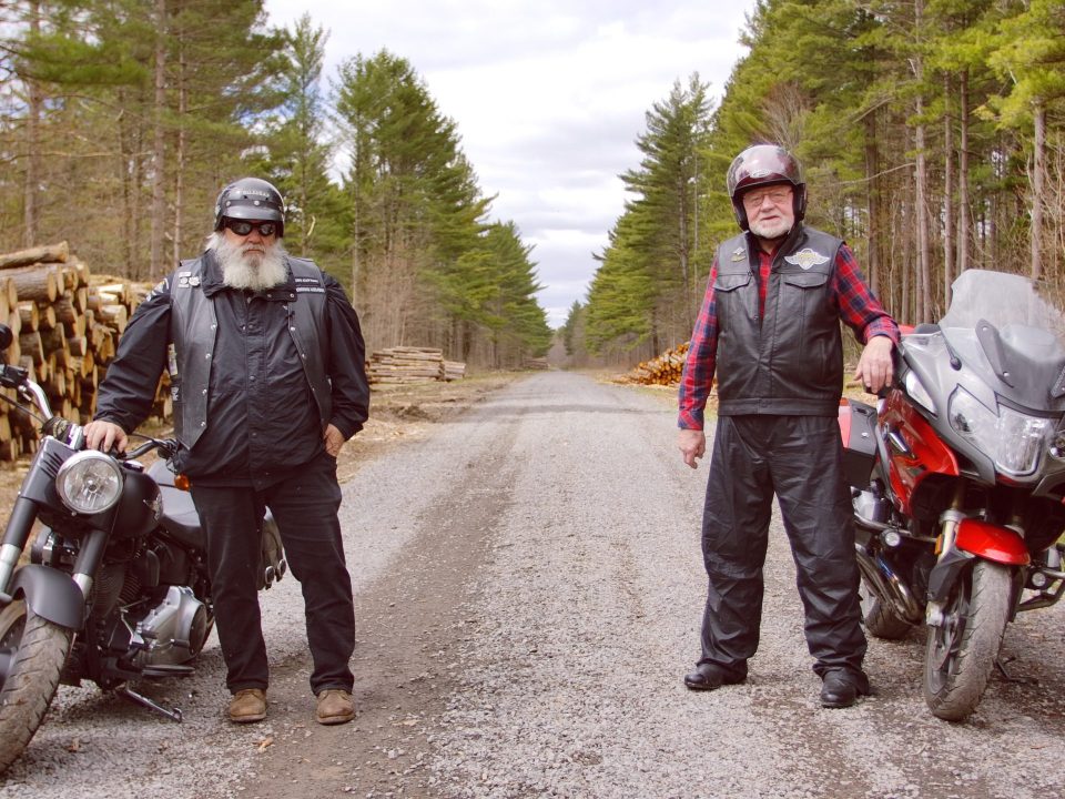 two men standing beside eachother with their motorcycle